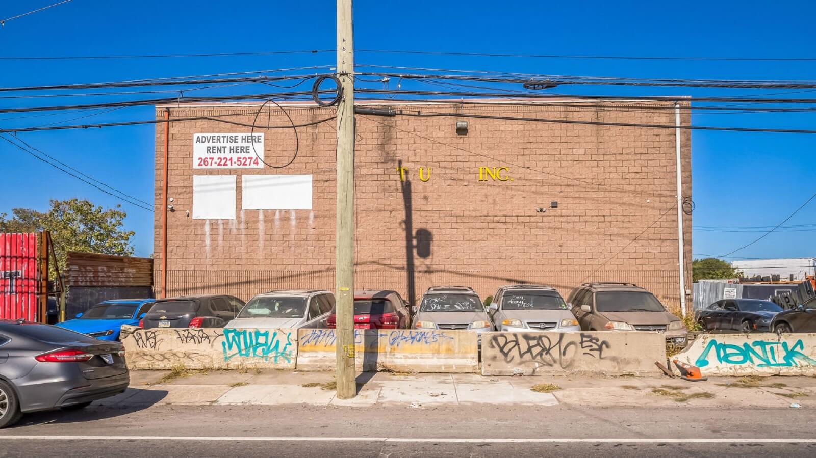 Graffiti-covered wall with parked cars.