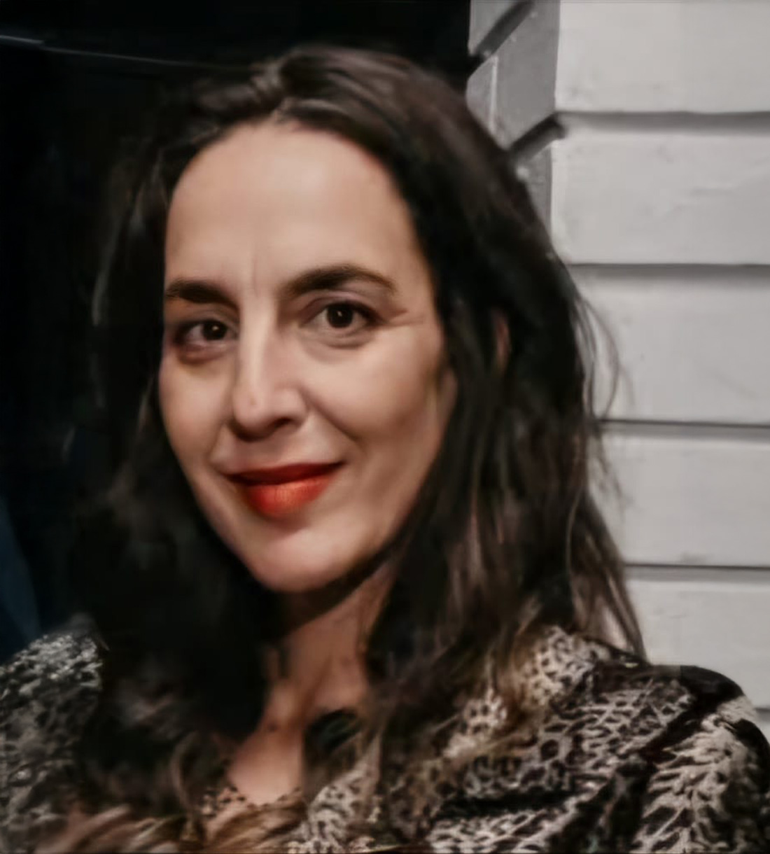 Woman smiling with long hair and lipstick.